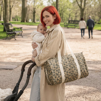 Sac a langer feuillu maman porte sur epaule tenant bebe